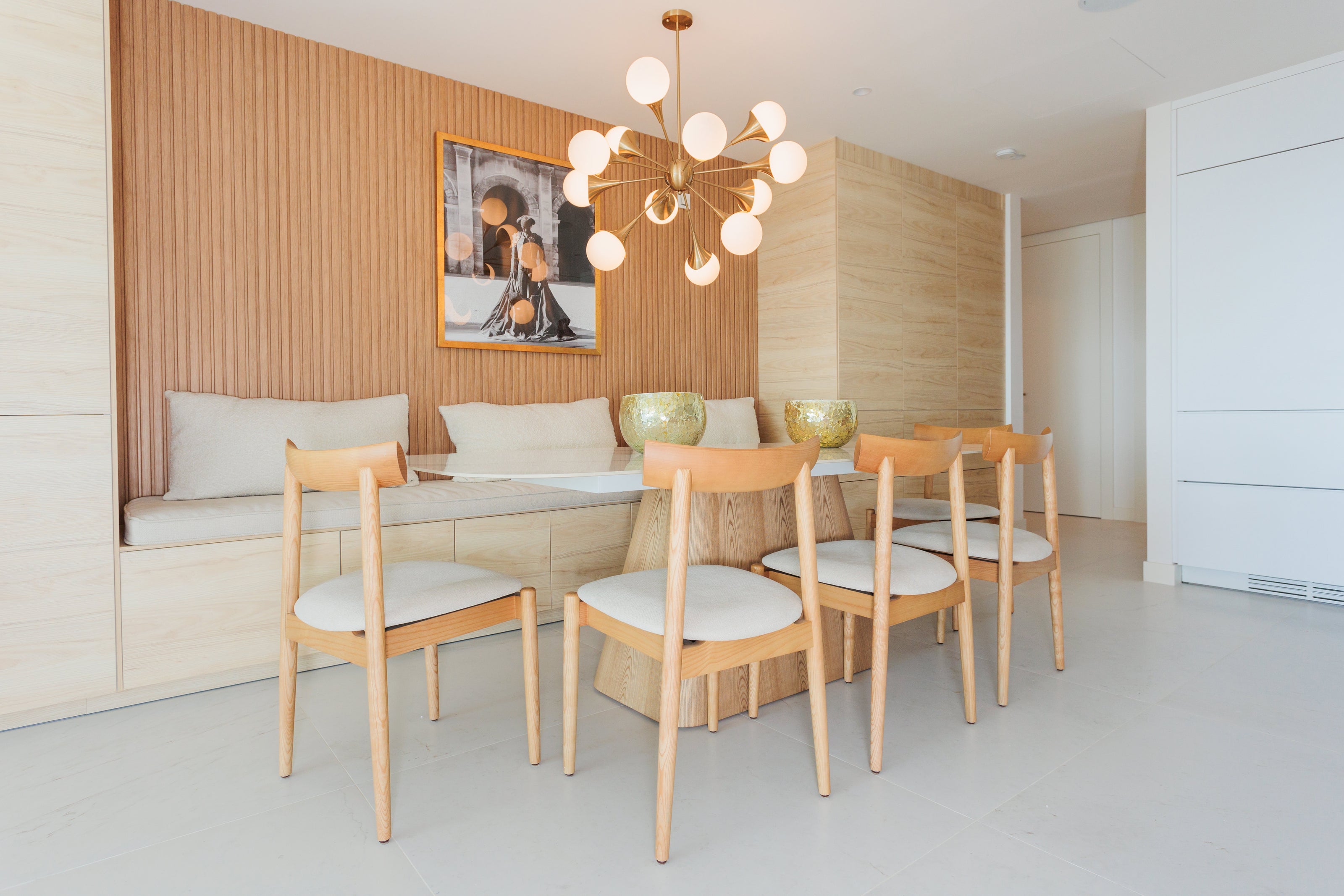 luxury interior design for dining room with wooden dining chairs, golden ceiling light, marble top and wooden legs dining tables, wooden panels, gold decors available in benahavis, marbella, malaga,  costadel sol.