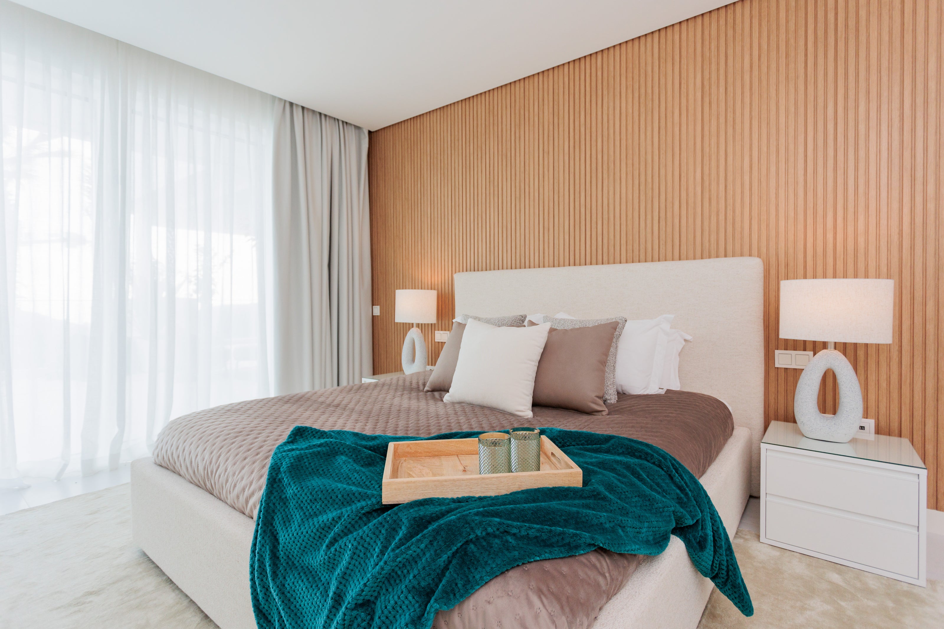 bedroom interior design with green and brown tones, modern cream bed, white bedside tables, oval table lamp available in marbella, alcazaba, malaga, costa del sol.