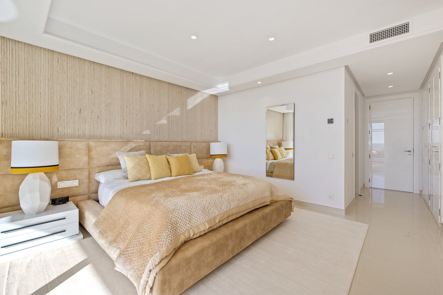 beautiful yellow modern bedroom interior design with long headboard and beige rug, bedside table with elegant table lamps available in malaga, marbella, costa del sol, benahavis.