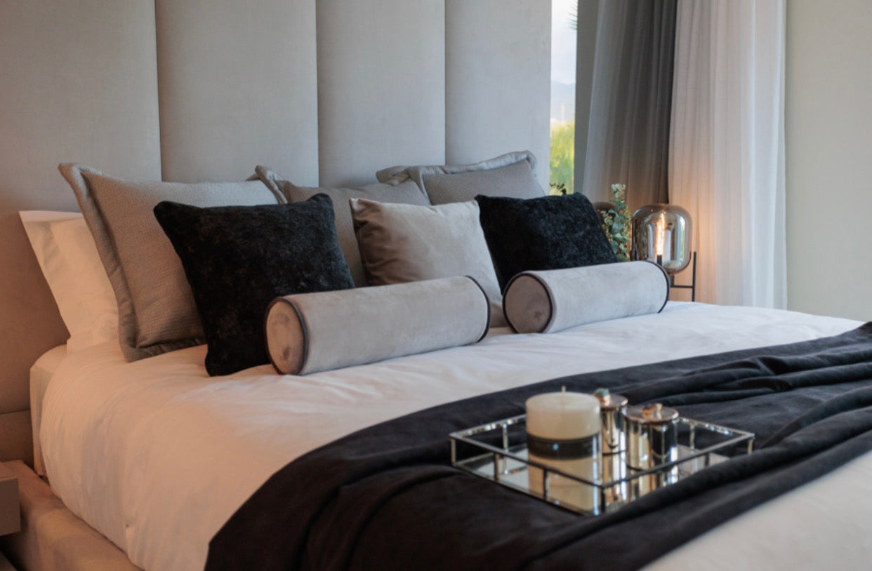 modern luxury interior design black and white bedroom with black pillows, elegant table lamp, silver tray, headboard with mirrors avaialble in bel air, marbella, malaga, estepona, costa del sol.