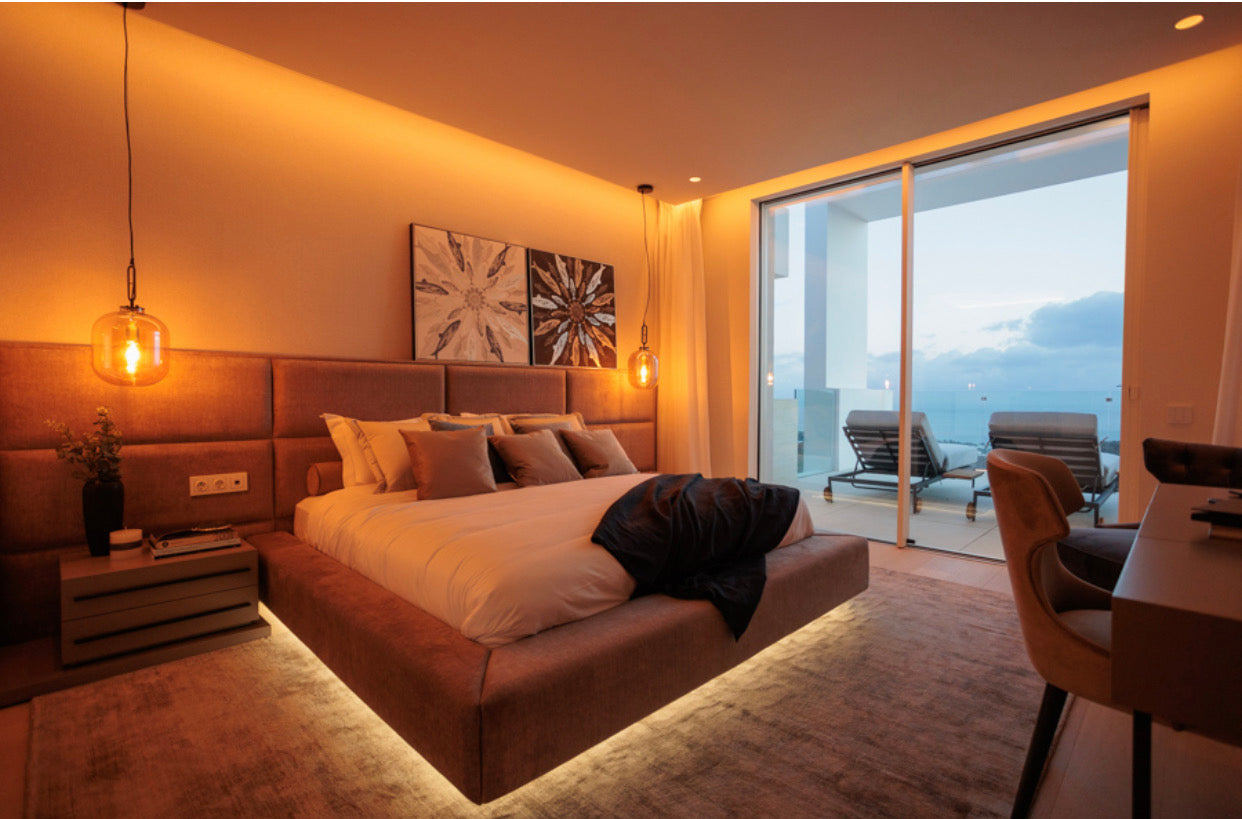 luxury interior design for bedroom with floating bed with led lights underneath, elegant headboard, paintings on the wall, bedside table, hanging celing lights, rugs available in bel air, marbella, malaga, costa del sol.