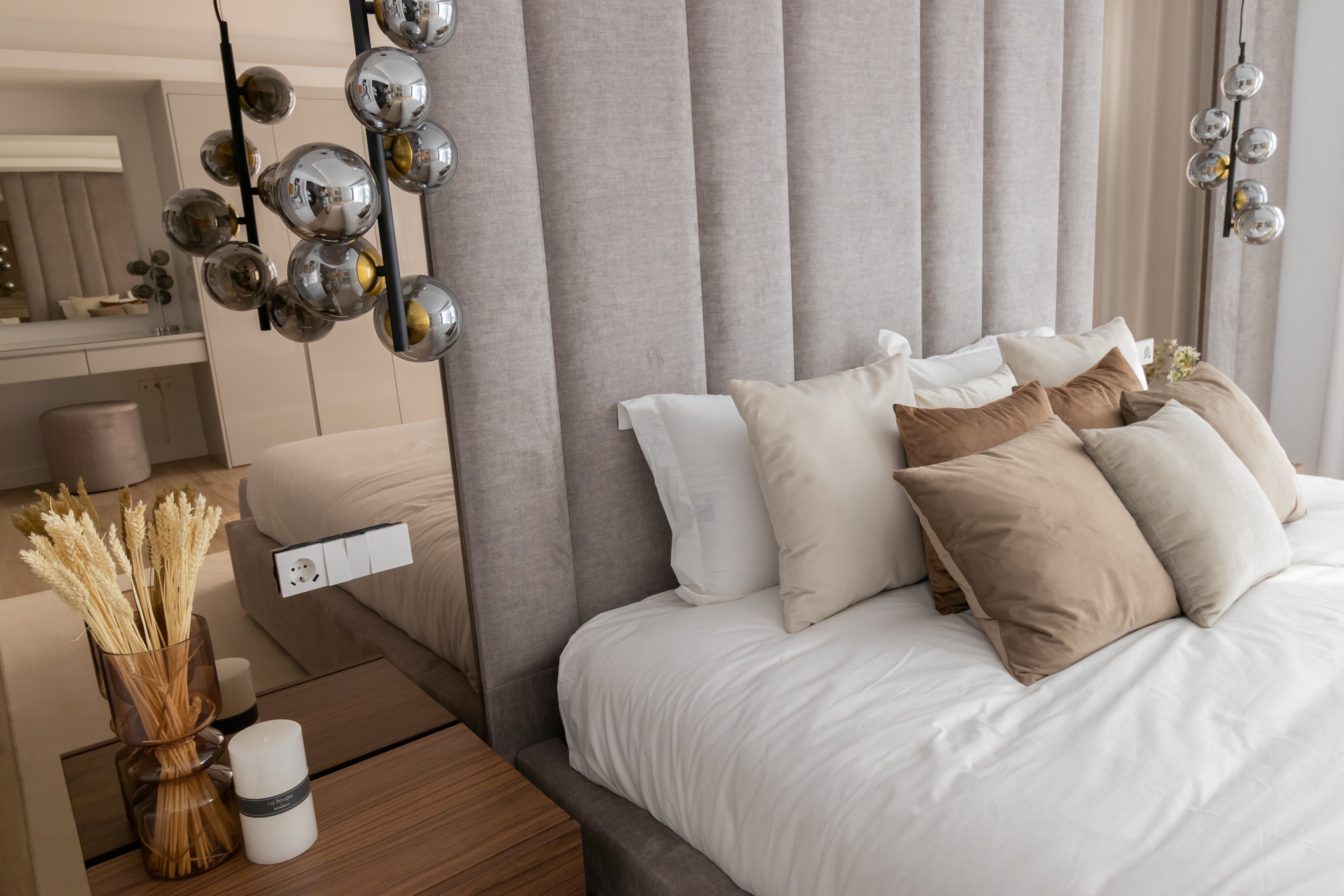luxury home furniture in bronze, brown warm tones, bronze mirror, wooden bedside table, circular ceiling lamps, headboard, brown pillows, and decors available in brisas del mar estepona interior design real estate.