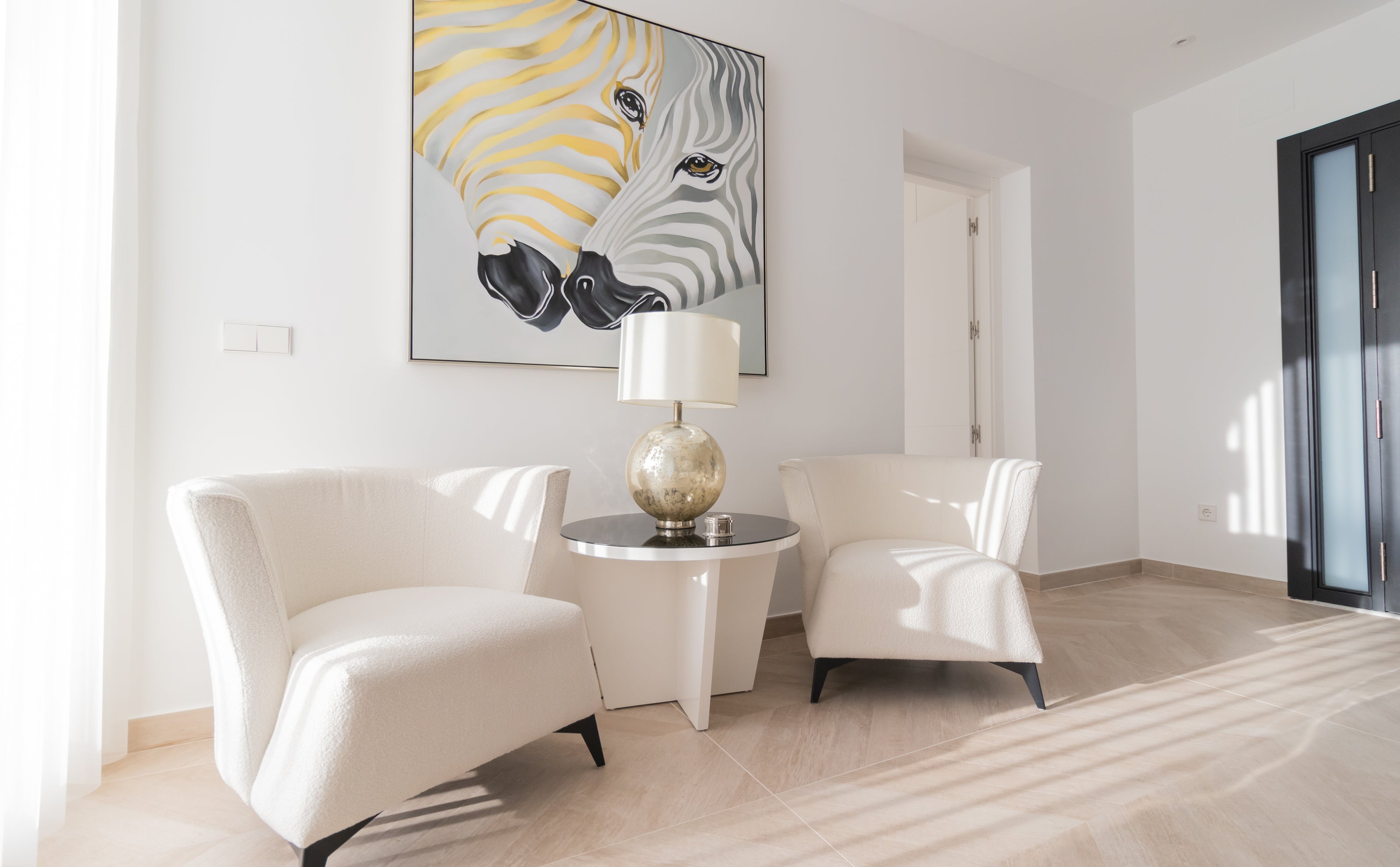 luxury interior design with 2 armchairs and modern side table, hanging zebra artwork with golden tones and table lamp available in calahonda, marbella, malaga, costa del sol.